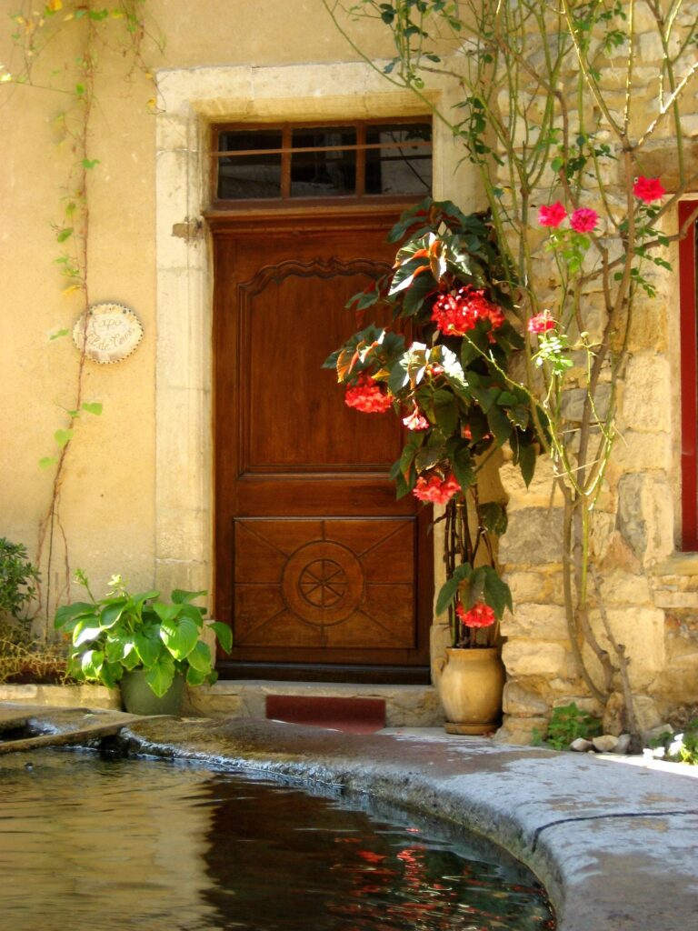 Porte ancienne décorée de fleurs colorées dans un village de Provence. Old doorway decorated with colorful flowers in a Provençal village.