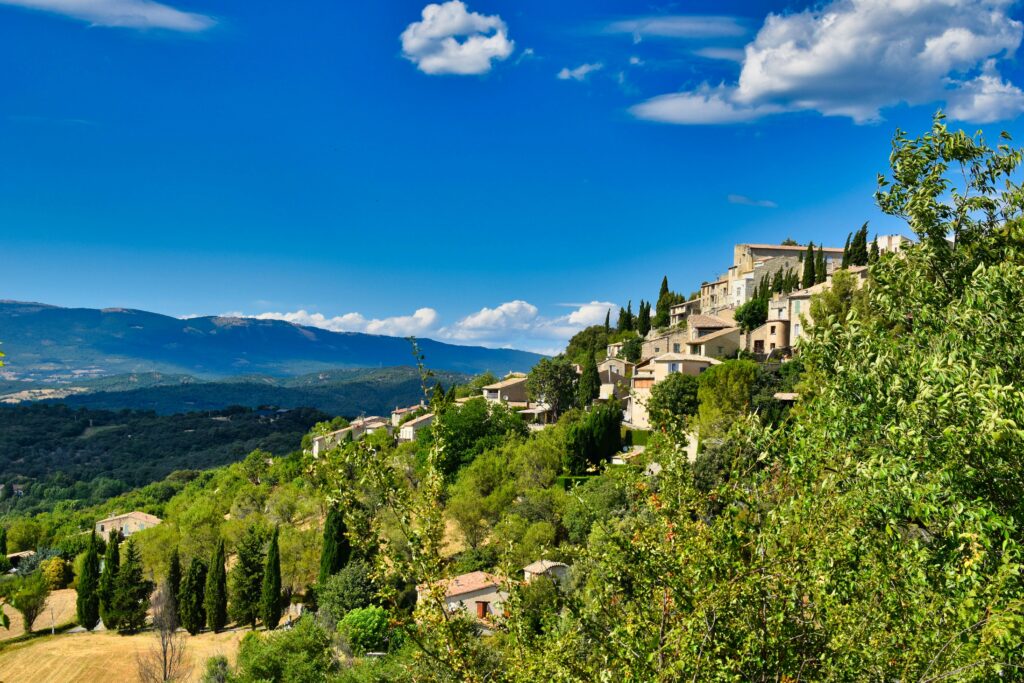 Village perché du Luberon, maisons en pierre et vue panoramique sur la vallée, Provence, France. Hilltop village in the Luberon with stone houses and panoramic valley views, Provence, France.