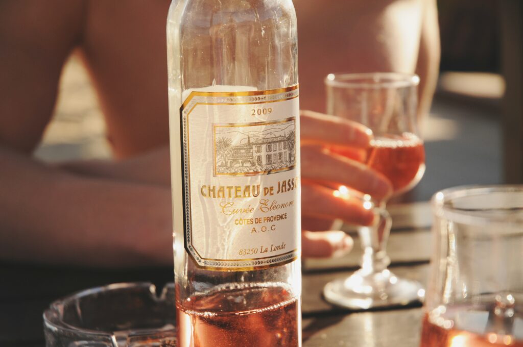 Bouteille de vin rosé posée sur une table en Provence, reflet du soleil du sud de la France. Bottle of rosé wine on a table in Provence, glowing under the southern French sun.
